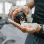 Sporty muscular man arms showing sports and fitness supplements