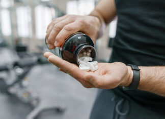 Sporty muscular man arms showing sports and fitness supplements