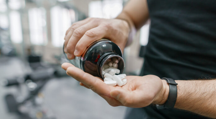 Sporty muscular man arms showing sports and fitness supplements