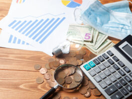 Pandemic cost with calculator, magnifier and coins