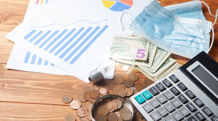 Pandemic cost with calculator, magnifier and coins