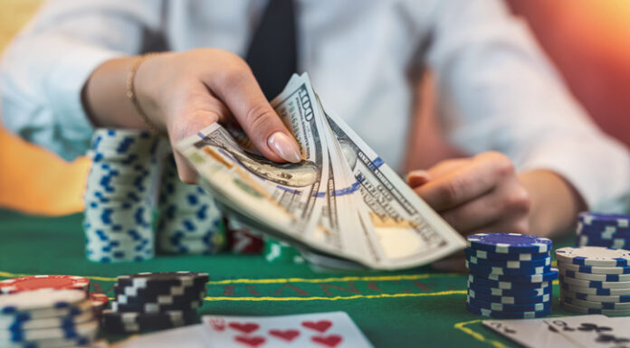 Female player counts chips for money and raises during poker game in casino.