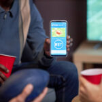 Online Betting in Botswana Close up of man holding smartphone with sports bets app