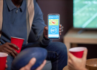 Close up of man holding smartphone with sports bets app