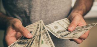 Instant Payday Loans – Pros, Cons, Risks, And Other Key Considerations A man in a gray T-shirt holds dollars in his hands. Bank. Casino. Salary. Rates