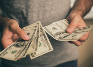 A man in a gray T-shirt holds dollars in his hands. Bank. Casino. Salary. Rates