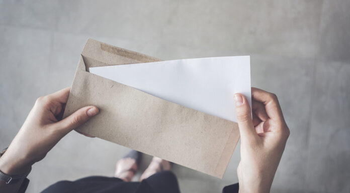 woman holding white folded a4 paper and brown envelope