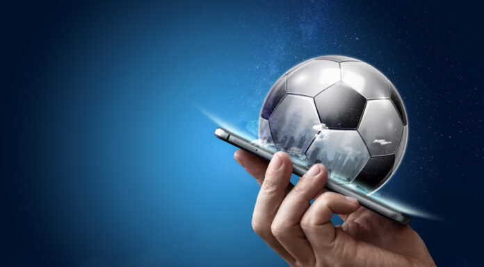 Why Football Betting is Increasing Day by Day? Smartphone in hand with a 3D soccer ball on a blue background