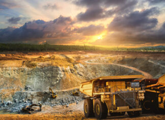 Yellow dump truck loading minerals copper, silver, gold, and other at mining quarry.