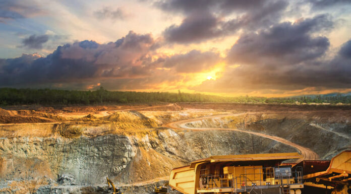 Yellow dump truck loading minerals copper, silver, gold, and other at mining quarry.