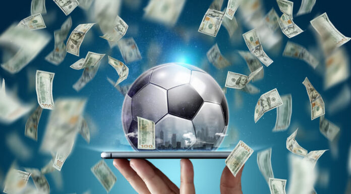 Dollars are falling on the background of a hand with a smartphone and a soccer ball