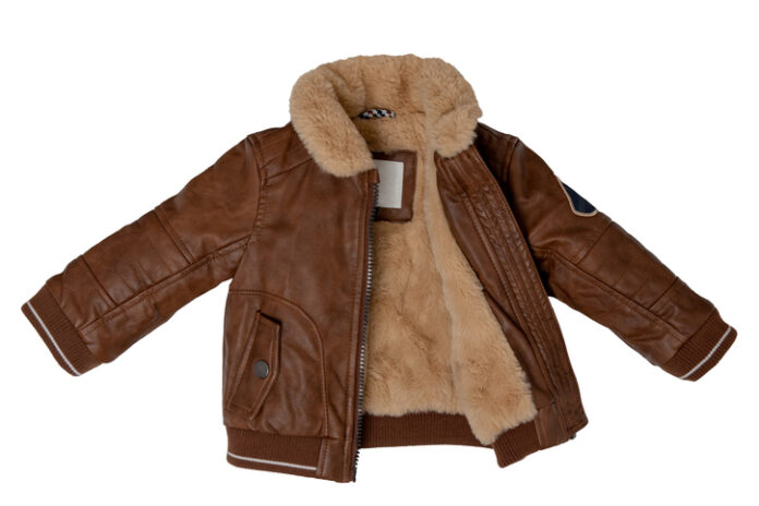 Top view of clothes for child boy isolated on a white background. Trendy stylish brown leather jacket with beige fur. Autumn and winter fashion for kids leather jacket