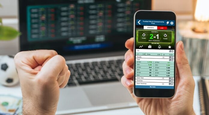 Male fist clenched with triumph in front of laptop screen.