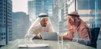 Healthy Workplaces in Dubai: Combating Desert Challenges Two Successful Emirati Businessmen in White Traditional Kandura Sitting in Office Meeting