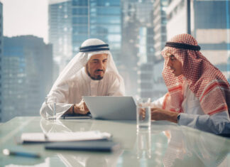 Two Successful Emirati Businessmen in White Traditional Kandura Sitting in Office Meeting