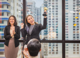 Budget-Friendly Yet Effective Employee Recognition Programs for Small Businesses Business woman holding award trophy