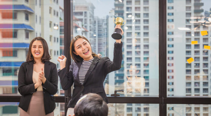 Budget-Friendly Yet Effective Employee Recognition Programs for Small Businesses Business woman holding award trophy