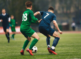 Adult football competition. Soccer football player dribbling a ball and kick a ball during match in the stadium