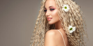 Elevate Your Style with a Stunning 20-Inch Hair Wig Portrait of young blonde haired beautiful model with flowers of chamomile in her long curly hairstyle. Soft smile on the attractive face.