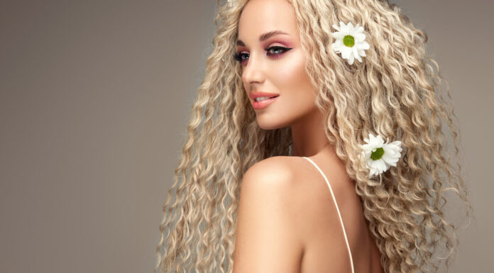 Elevate Your Style with a Stunning 20-Inch Hair Wig Portrait of young blonde haired beautiful model with flowers of chamomile in her long curly hairstyle. Soft smile on the attractive face.