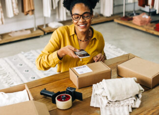 Female dropshipper uses a smartphone to scan the QR code for an online clothing order