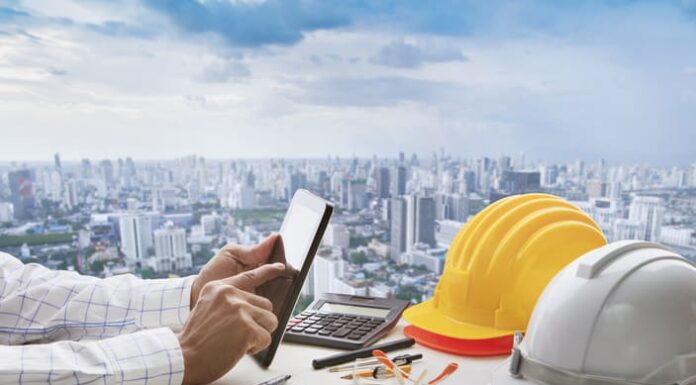 Your Guide to the Right Contractor Accommodation in the UK Hand of business man touching on computer tablet screen and safety helmet on working table against cities of high building for accommodation