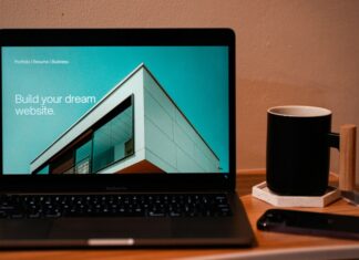 Build your dream website for your future. A laptop, MacBook, on top of a portable table with coffee tea mug on the side.