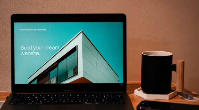 Build your dream website for your future. A laptop, MacBook, on top of a portable table with coffee tea mug on the side.