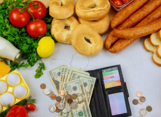 Produce with wallet and money on white table.