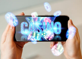 In a man's hand a smartphone with playing neon cards, chips, dice