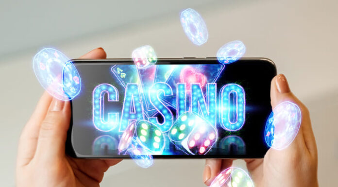 In a man's hand a smartphone with playing neon cards, chips, dice