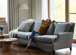 Happy carefree young female homeowner resting on comfortable couch.