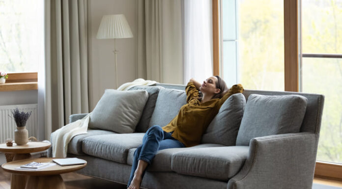 Happy carefree young female homeowner resting on comfortable couch.