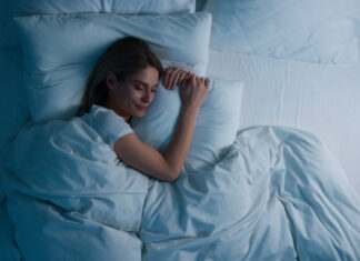 Woman sleeping in bed at night, above view.