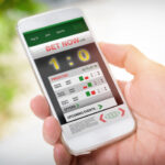 MelBet Mobile App Review: Convenience and Functionality Man holding smart phone with working online betting mobile application