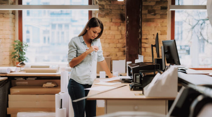 Embracing Tomorrow: Why Your Office Must Adopt Innovative Communication and Complimentary Printing Solutions Today Portrait of charming woman in blue shirt looking at notes while standing near table with printer