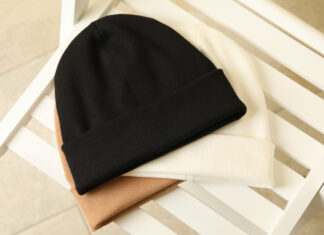 Three stylish beanies on wooden chair, top view