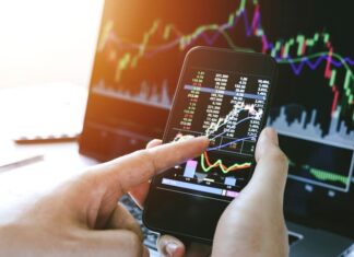 Businessman hand holding phone and analysis finance market graph stock market trading