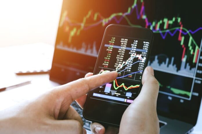 Businessman hand holding phone and analysis finance market graph stock market trading