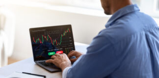 Tether’s Legal Woes businessman working on laptop, sitting at desk in office, typing on keyboard, trading online, buying or selling bitcoins, cryptocurrency,