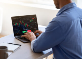 Tether’s Legal Woes businessman working on laptop, sitting at desk in office, typing on keyboard, trading online, buying or selling bitcoins, cryptocurrency,