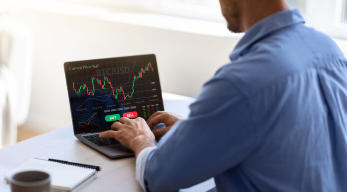 Tether’s Legal Woes businessman working on laptop, sitting at desk in office, typing on keyboard, trading online, buying or selling bitcoins, cryptocurrency,