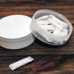 Snus box with nicotine pouches on wooden background