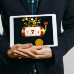 man in suit holding tablet with casino slot with jack pot on screen