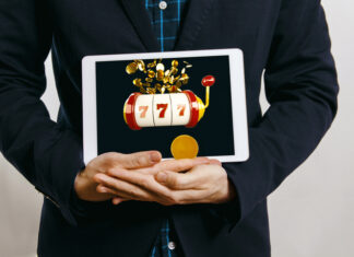 man in suit holding tablet with casino slot with jack pot on screen
