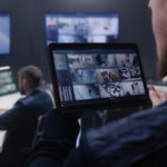 Close up shot of security officer zooming CCTV cameras with AI facial scanning