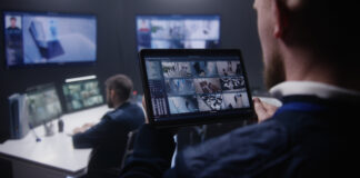 Streamlining Real-Time Video Monitoring: Solutions for Managing Data at the Source Ā Close up shot of security officer zooming CCTV cameras with AI facial scanning