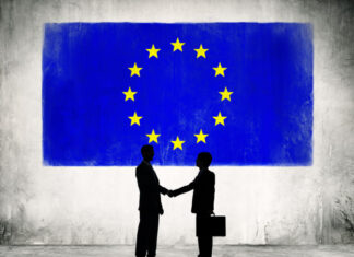 Business in Europe with the New Trump Administration Two Business Person Shaking Hands with the European Union Flag