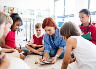 Hands-On Learning: Engaging Minds Through Real-World Experiences A group of small school kids with teacher sitting on the floor in class, learning