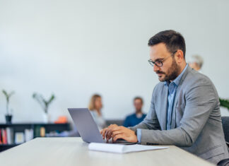 10 Benefits of Microlearning in the Workplace Serious-looking businessman using a modern technology, a laptop.